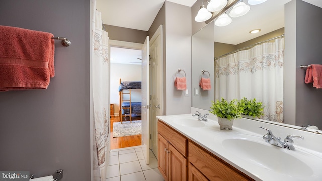 ensuite bathroom featuring tile patterned flooring, double vanity, connected bathroom, and a sink