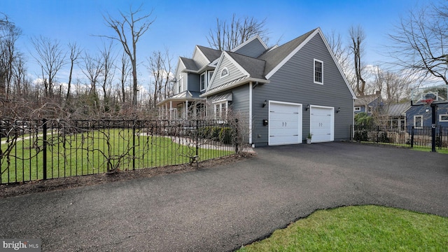 view of side of home with aphalt driveway, an attached garage, fence, and a lawn