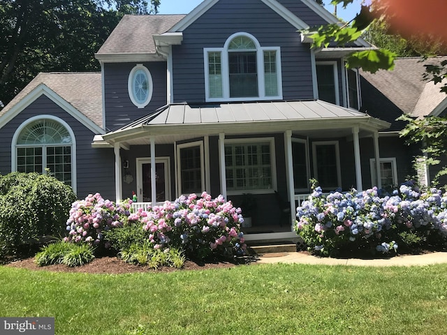 view of front of home with covered porch, a shingled roof, a standing seam roof, and metal roof