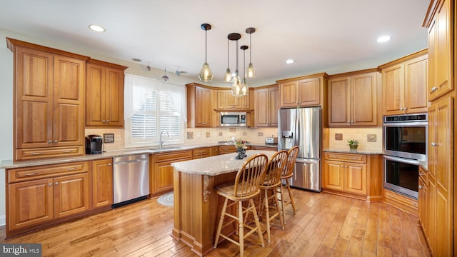 kitchen with light stone counters, decorative backsplash, light wood-style floors, stainless steel appliances, and a sink