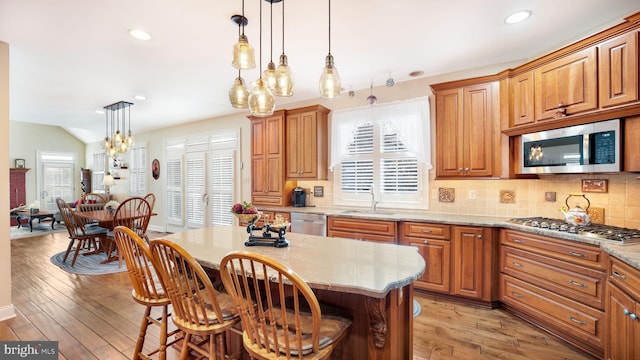 kitchen with light wood-style flooring, tasteful backsplash, appliances with stainless steel finishes, and a center island