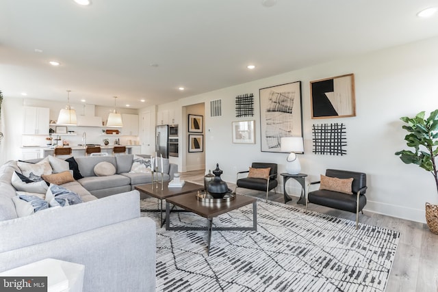 living area with light wood finished floors, recessed lighting, and baseboards