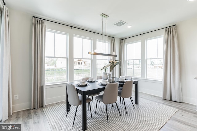 dining room with a healthy amount of sunlight, visible vents, light wood finished floors, and baseboards