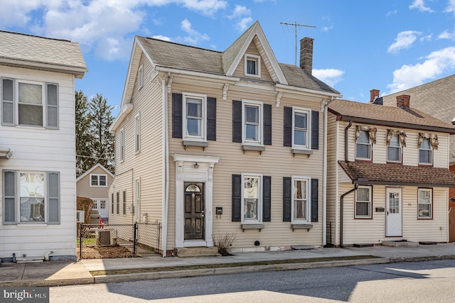 view of front of home with fence, entry steps, central AC, a chimney, and a gate