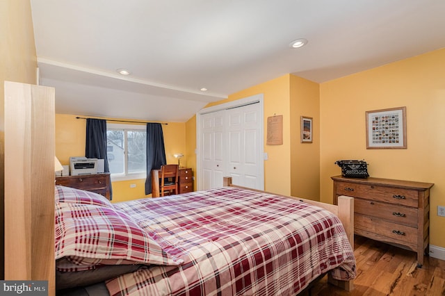 bedroom featuring wood finished floors, recessed lighting, a closet, baseboards, and vaulted ceiling