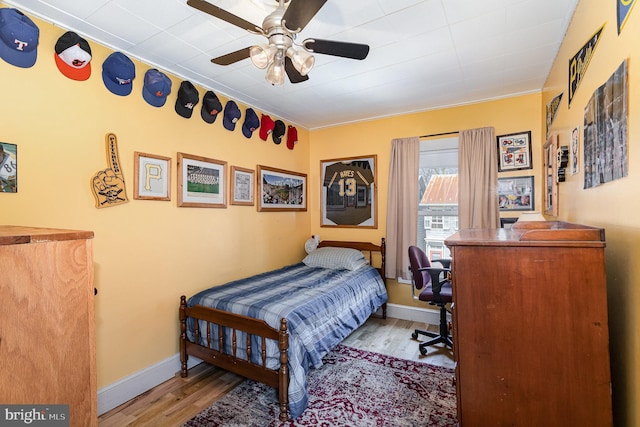 bedroom with ceiling fan, baseboards, and wood finished floors