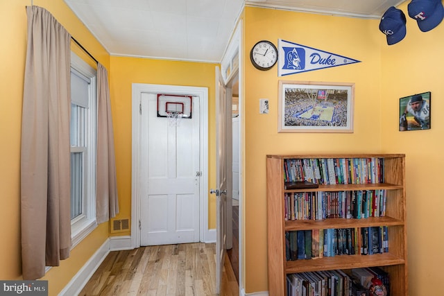 hall featuring visible vents, baseboards, and wood finished floors