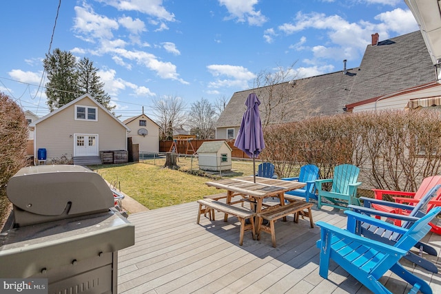 deck featuring outdoor dining space, fence, an outdoor structure, french doors, and a lawn