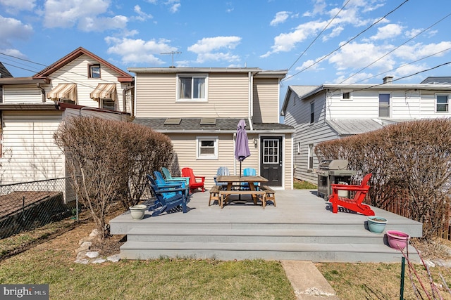 rear view of property with a deck, fence, and a shingled roof