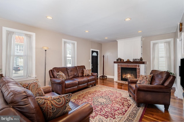 living area featuring a fireplace, plenty of natural light, wood finished floors, and recessed lighting