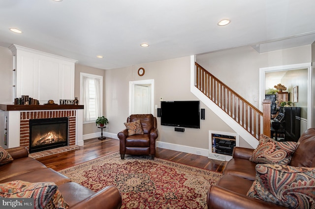 living area with stairway, wood-type flooring, baseboards, and a fireplace