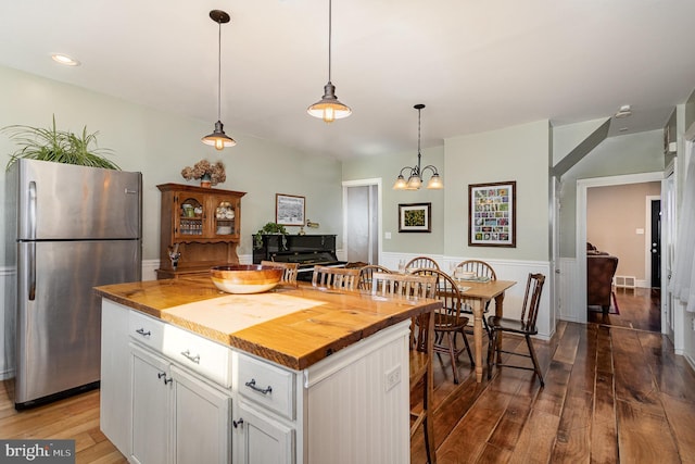 kitchen with hardwood / wood-style flooring, decorative light fixtures, white cabinetry, freestanding refrigerator, and wooden counters