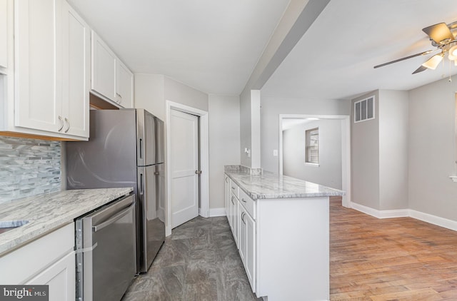 kitchen featuring visible vents, light stone counters, appliances with stainless steel finishes, a peninsula, and white cabinets