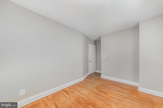 spare room with baseboards and light wood finished floors