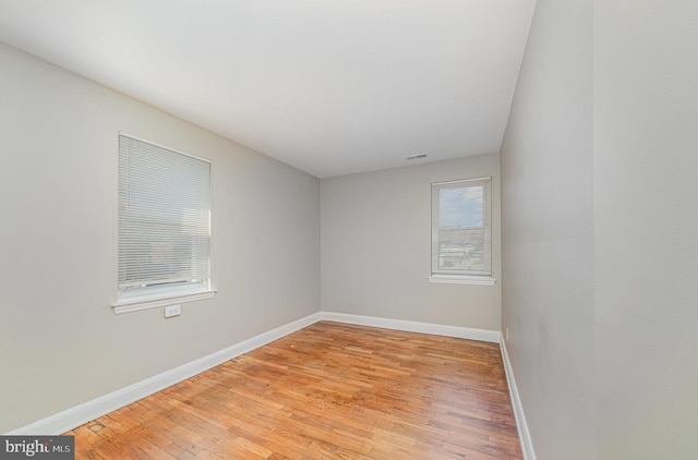 unfurnished room with visible vents, light wood-style flooring, and baseboards