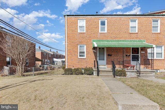 view of front of property with brick siding, a front lawn, and fence