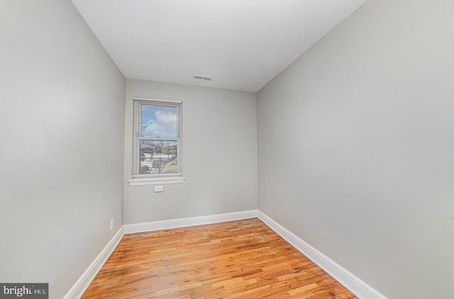 empty room with light wood finished floors, visible vents, and baseboards