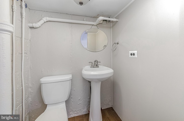 half bathroom with toilet and wood finished floors