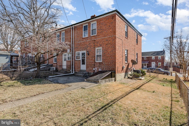 back of house with a yard, brick siding, fence private yard, and entry steps