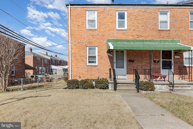 view of front of home featuring a front lawn, fence, and brick siding