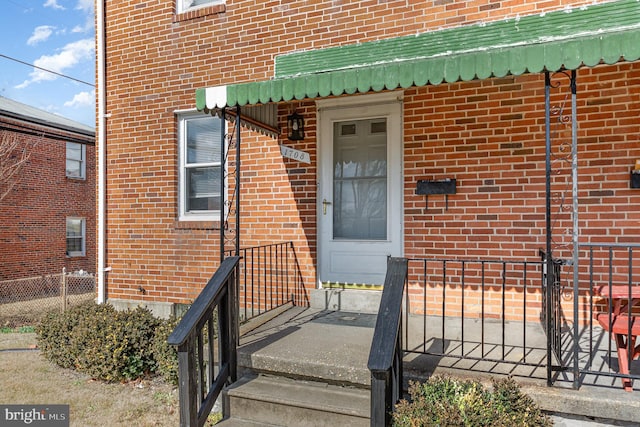 entrance to property with brick siding and fence