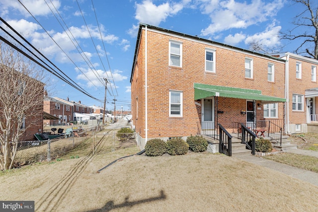 view of property featuring brick siding, a front yard, and fence