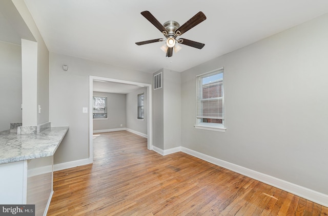 interior space with light wood finished floors, visible vents, a healthy amount of sunlight, and baseboards