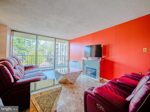 living area with a glass covered fireplace, a textured ceiling, and a wall of windows