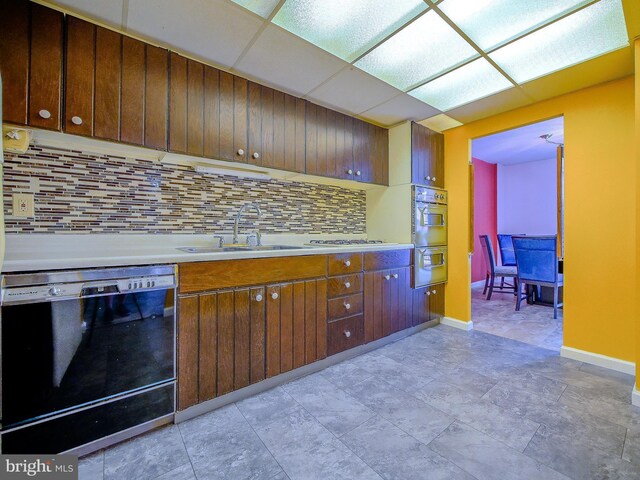 kitchen with baseboards, a sink, light countertops, black dishwasher, and backsplash