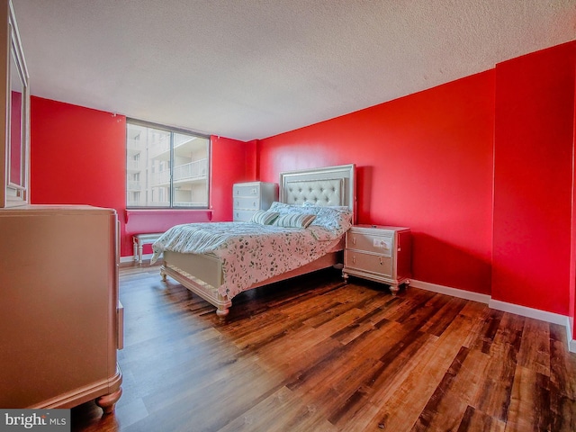 bedroom featuring a textured ceiling, baseboards, and wood finished floors