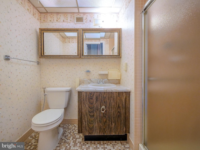 bathroom featuring wallpapered walls, toilet, vanity, and a stall shower