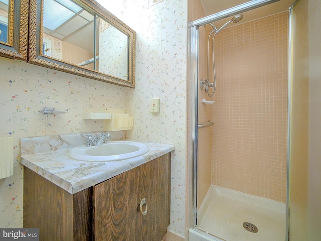 bathroom with a stall shower, wallpapered walls, and vanity