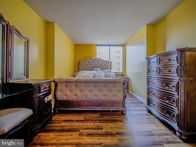 bedroom featuring baseboards, dark wood-style flooring, and a textured ceiling