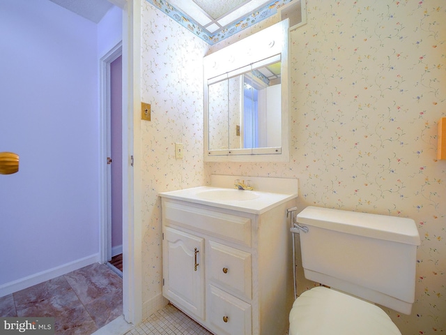 bathroom with tile patterned flooring, wallpapered walls, toilet, a skylight, and vanity