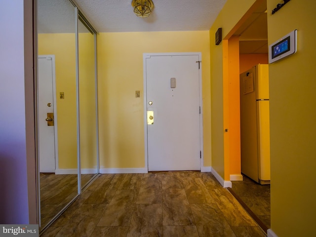 interior space with a textured ceiling and baseboards