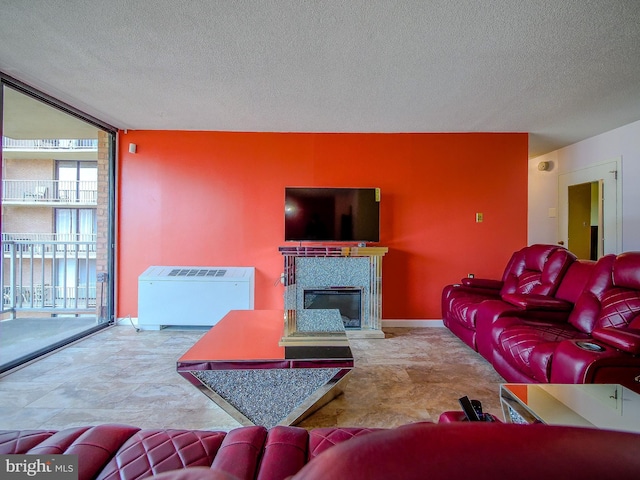 living area featuring floor to ceiling windows, a tile fireplace, a textured ceiling, and baseboards