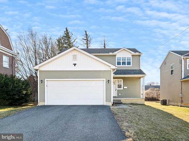 view of front of house featuring a front yard, cooling unit, driveway, roof with shingles, and an attached garage