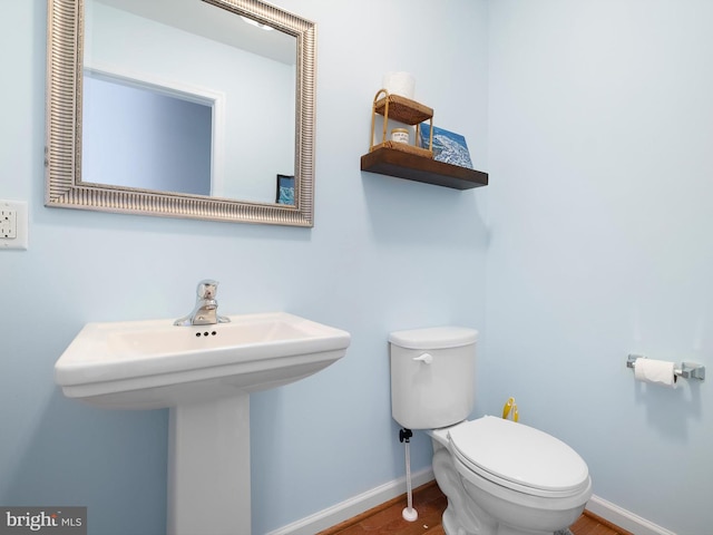 bathroom featuring toilet, baseboards, and a sink