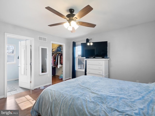 bedroom with visible vents, a walk in closet, baseboards, wood finished floors, and a closet