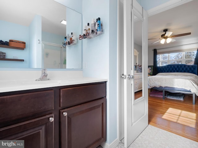 bathroom with a ceiling fan, wood finished floors, ensuite bath, a shower stall, and vanity