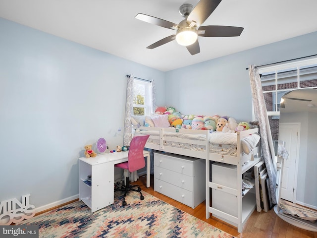 bedroom featuring baseboards, wood finished floors, and a ceiling fan