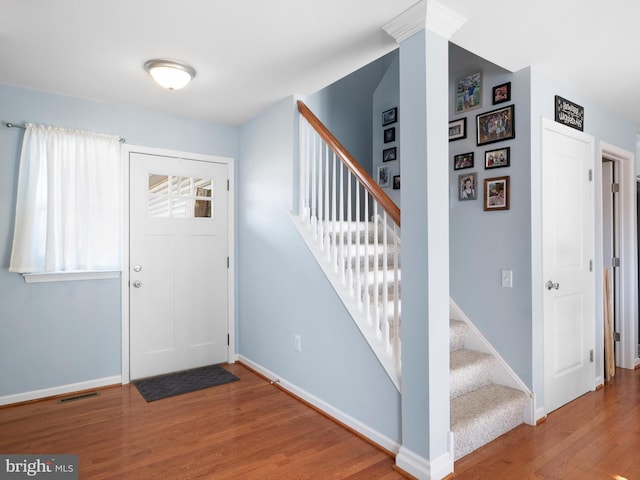 entryway with visible vents, baseboards, wood finished floors, and stairs