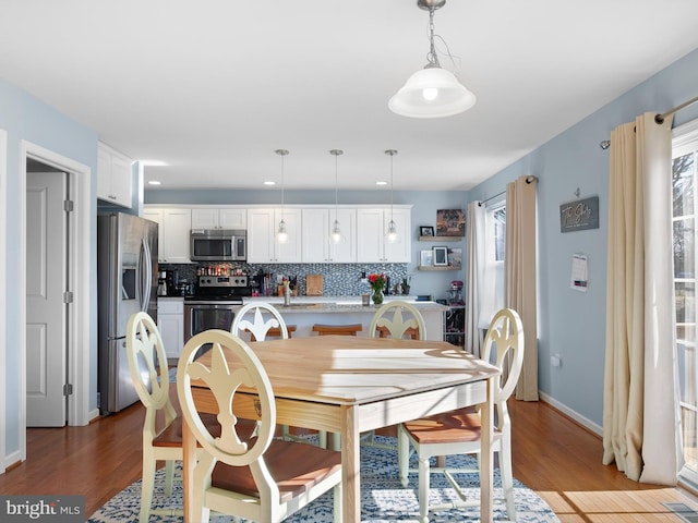 dining room featuring light wood finished floors, visible vents, a healthy amount of sunlight, and baseboards