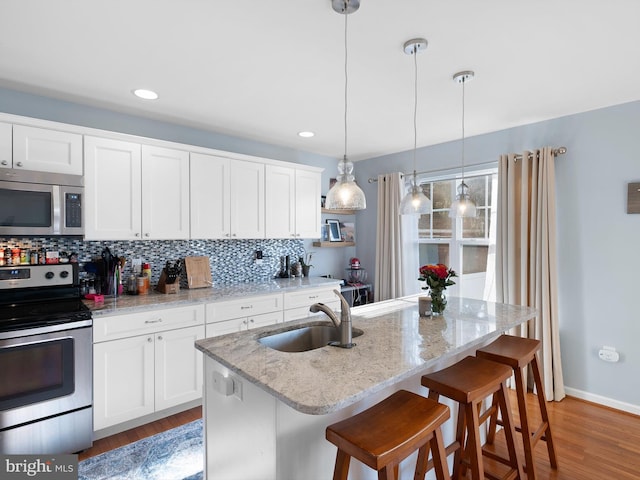 kitchen featuring decorative backsplash, white cabinets, appliances with stainless steel finishes, and a sink