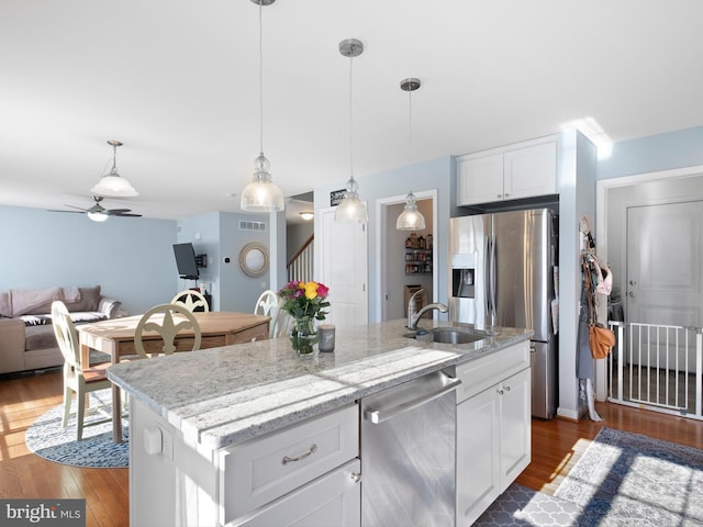 kitchen featuring dark wood-style floors, a sink, stainless steel appliances, white cabinets, and open floor plan