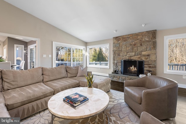 living room featuring lofted ceiling, light wood-style flooring, a fireplace, and baseboards