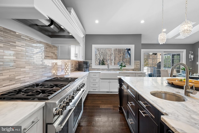 kitchen featuring a sink, white cabinets, light stone countertops, and range with two ovens