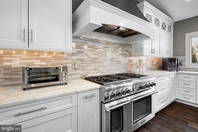 kitchen featuring light stone countertops, dark wood finished floors, range with two ovens, custom exhaust hood, and white cabinets