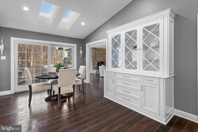 dining space with dark wood finished floors, recessed lighting, vaulted ceiling with skylight, and baseboards