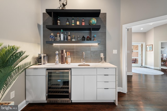 bar featuring tasteful backsplash, dark wood-type flooring, beverage cooler, indoor wet bar, and a sink